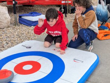 From the left, Matthew Wurst, 8, and his brother Adam, 9, of Rock Springs, Wyo., play floor curling at the fan festival outside the 2026 World Men's Curling Championship on Saturday, March 28, 2026, in Ogden, Utah. (Ryan Olson, Standard-Examiner)